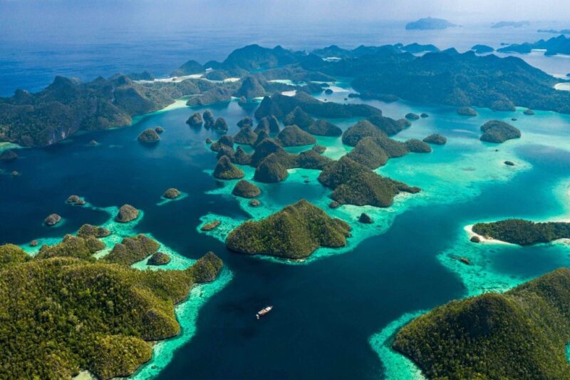 Pemandangan laut biru jernih dengan gugusan pulau karst hijau di Raja Ampat, Papua Barat.