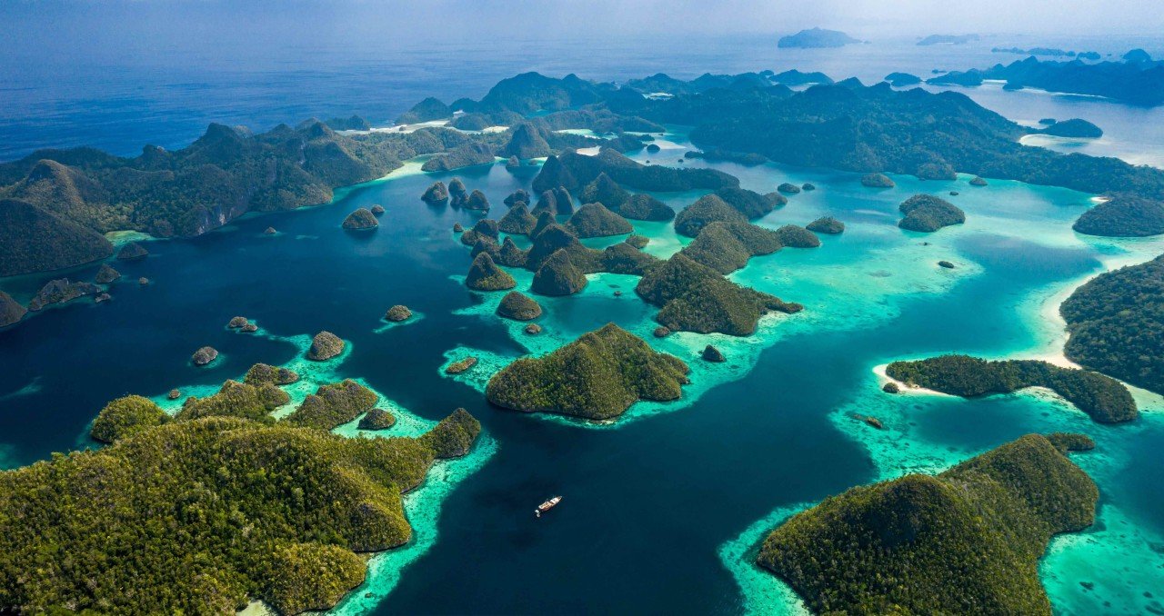 Pemandangan laut biru jernih dengan gugusan pulau karst hijau di Raja Ampat, Papua Barat.